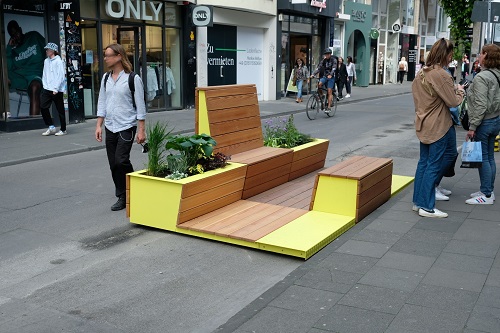 Sitzmöglichkeiten aus Holz mit Begrünung auf der Ehrenstraße