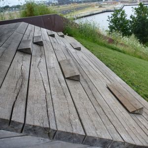 Auf Holz sind Balken versehen, auf die man sich hinsetzen kann