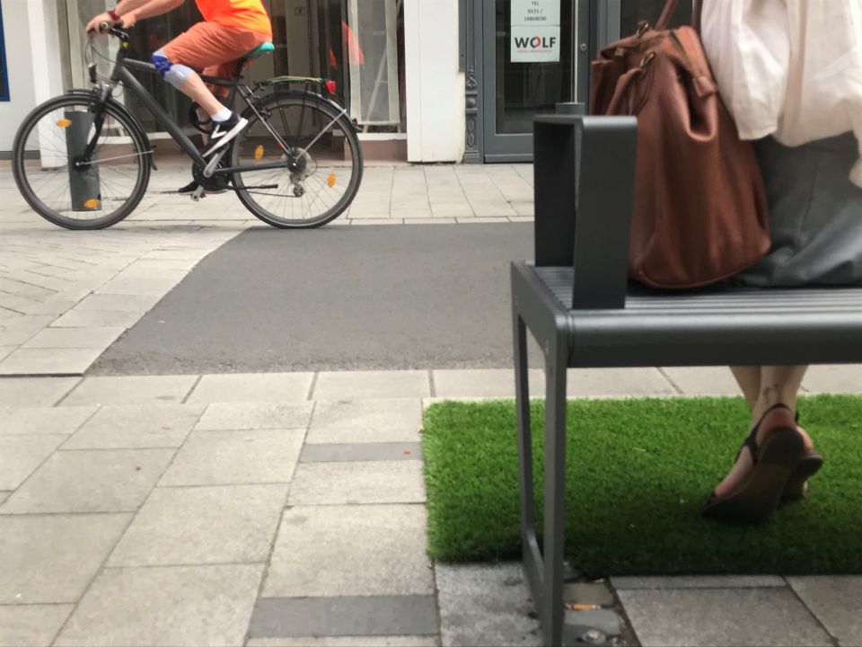 Frau auf einer Bank und Fahrradfahrer im Hintergrund