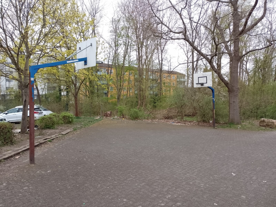 offener, asphaltierter Basketballplatz neben Parkplatz