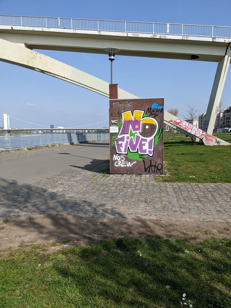 Mit Graffiti besprühtes Toilettenhaus mit öffentlichen Toiletten am Rhein.