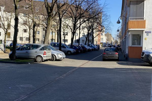 Zu sehen ist der Bereich Markt zwischen Steprathstraße und Markt 6. Links parken Autos in Parktaschen. Rechts stehen parkende Autos vor einem Wohnhaus.