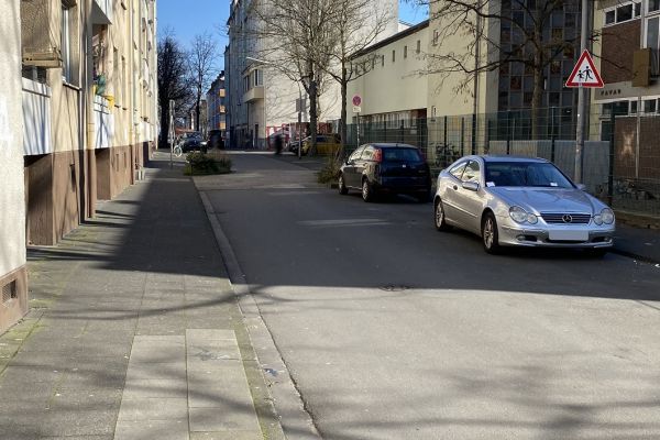 Zu sehen ist der Bereich Markt zwischen Markt 6 und Josephkirchstraße. Links ist ein Bürgersteig. Rechts parken vereinzelt Autos. Ein Verkehrsschild weist auf spielende Kinder hin.