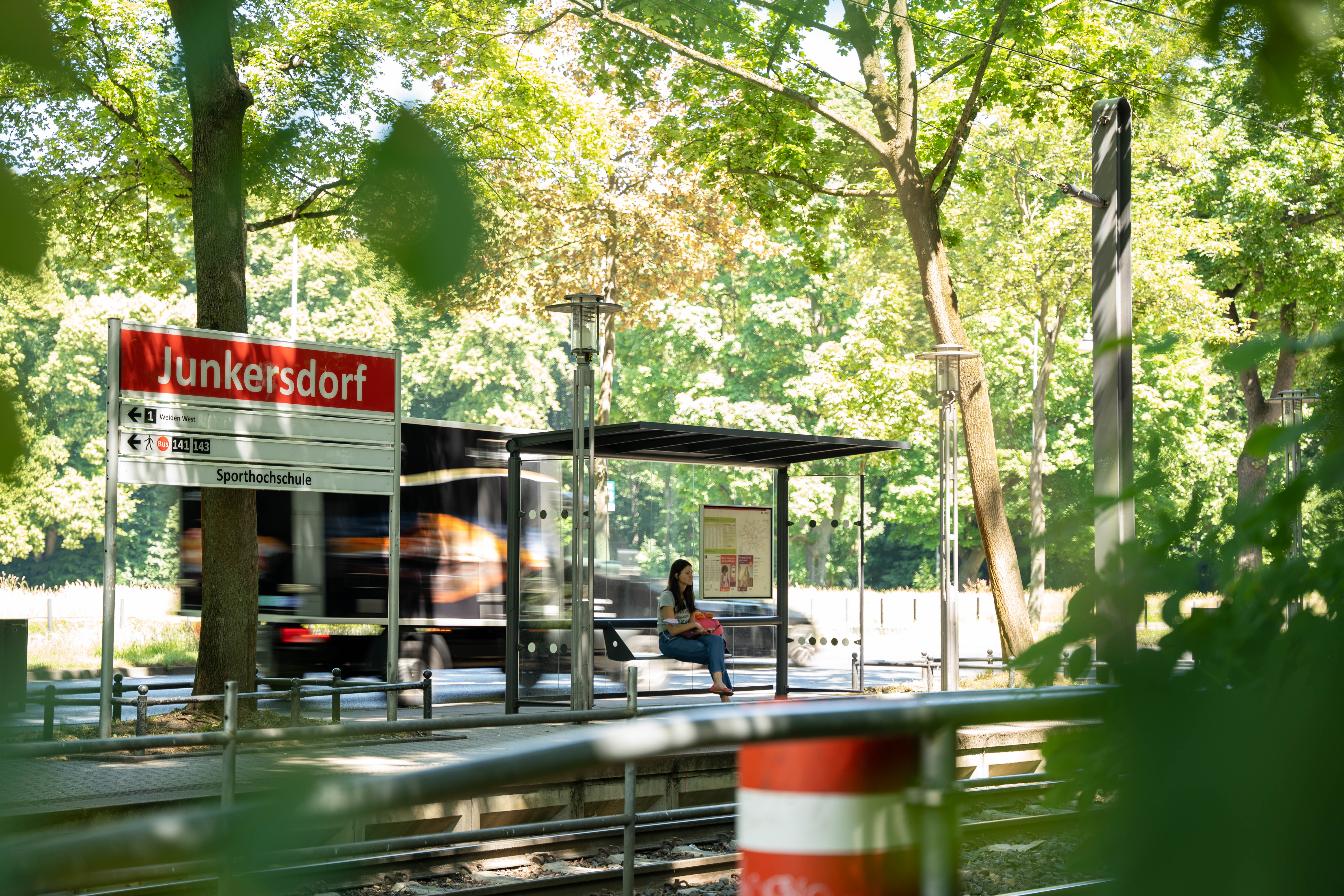 Blick von der gegenüberliegenden Seite auf den Bahnsteig und das Haltestellenschild Junkersdorf 