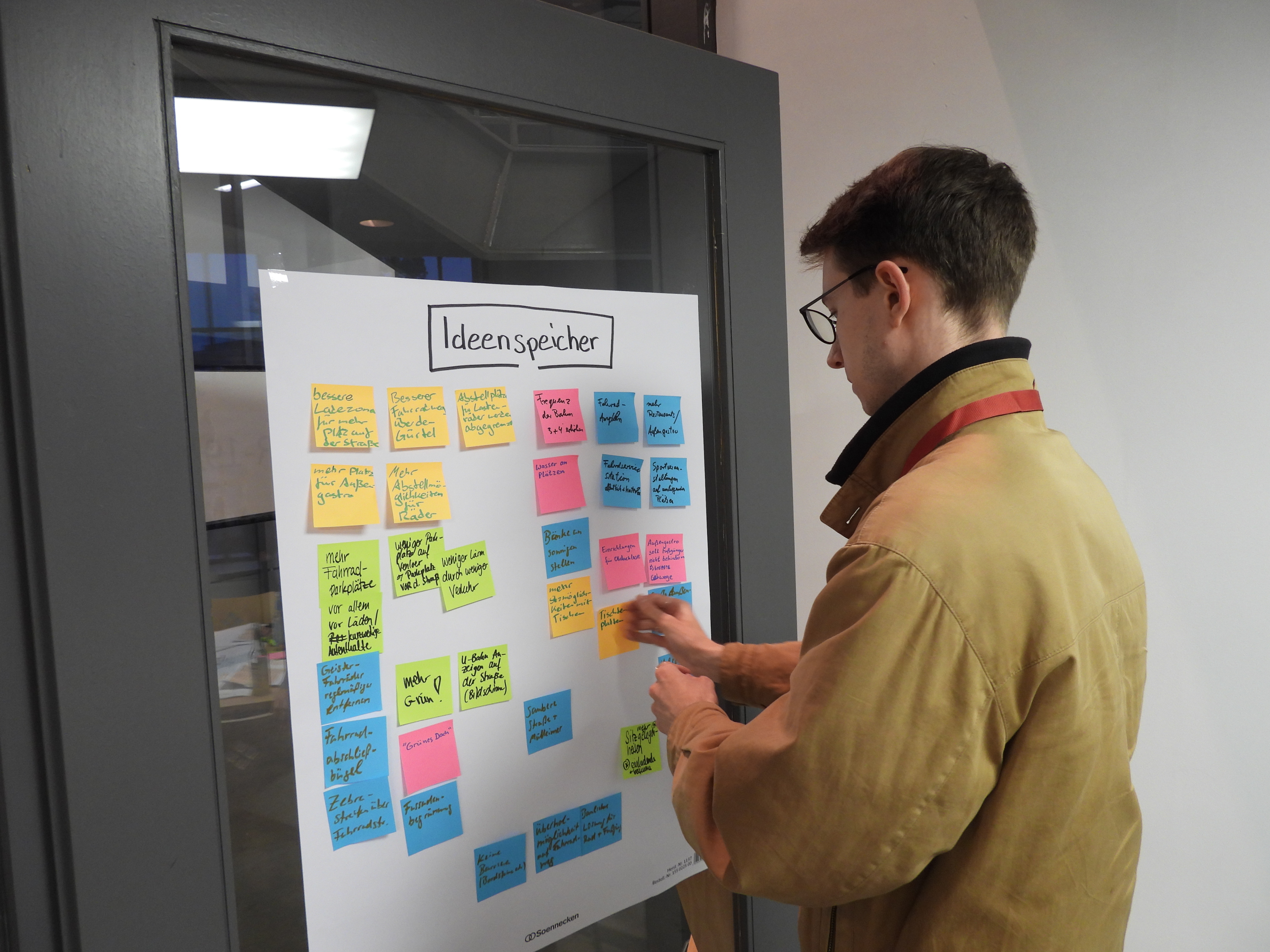 Mensch an Wand mit Post-Its und Ideen