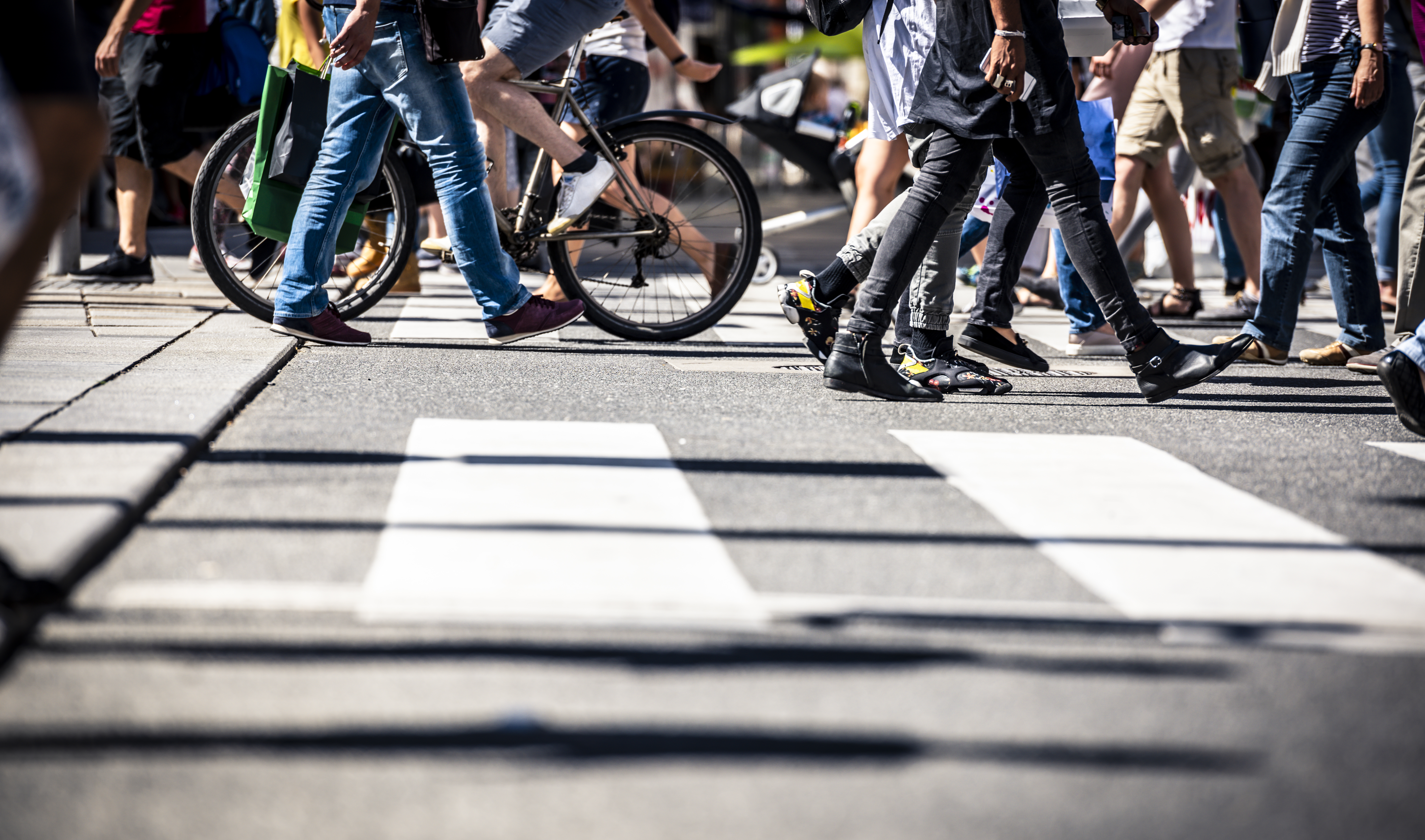 Viele Menschen gehen zu Fuß in der Innenstadt über einen Zebrastreifen.