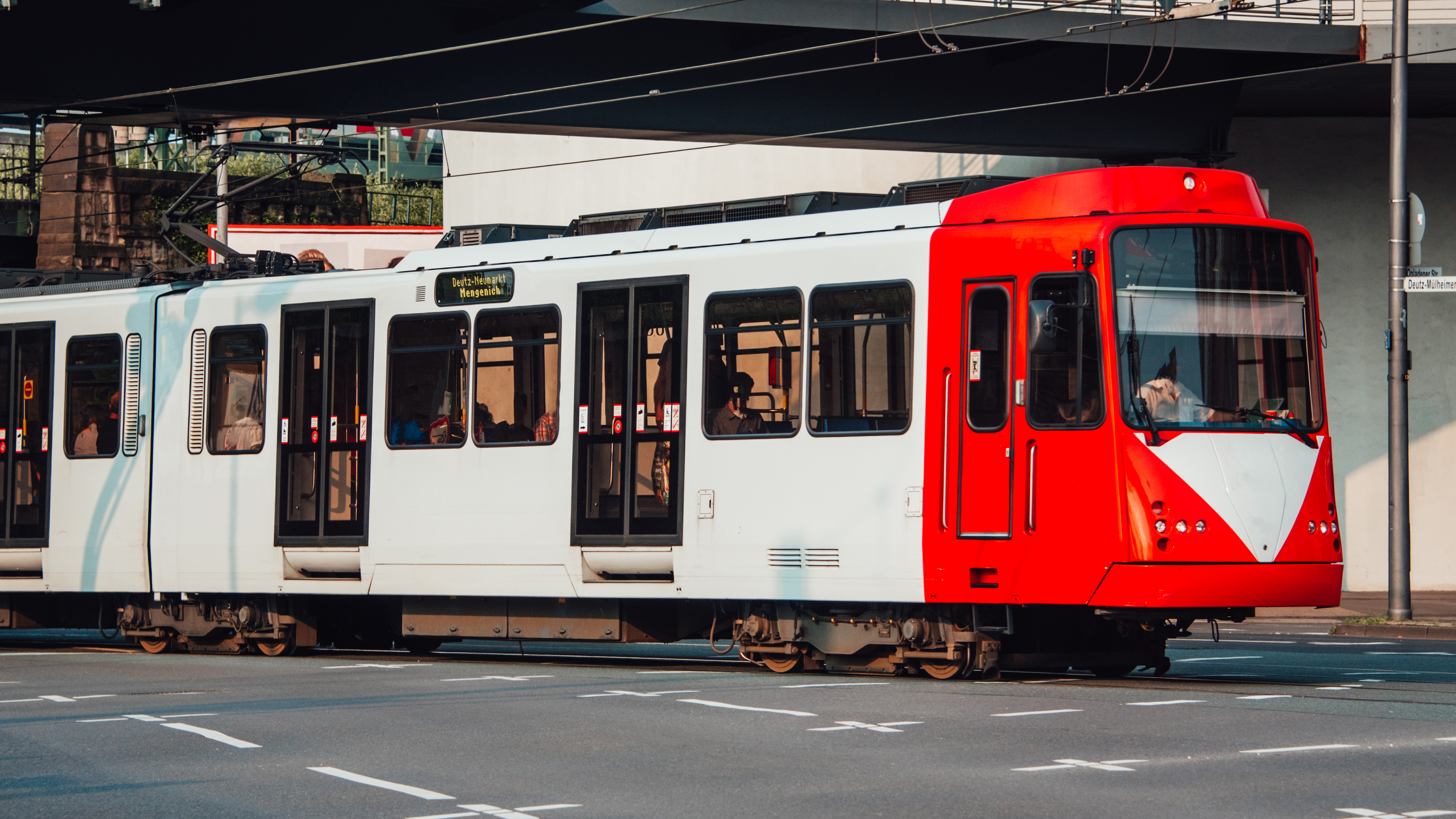 Eine rot-weiße Straßenbahn fährt durch eine Straße.