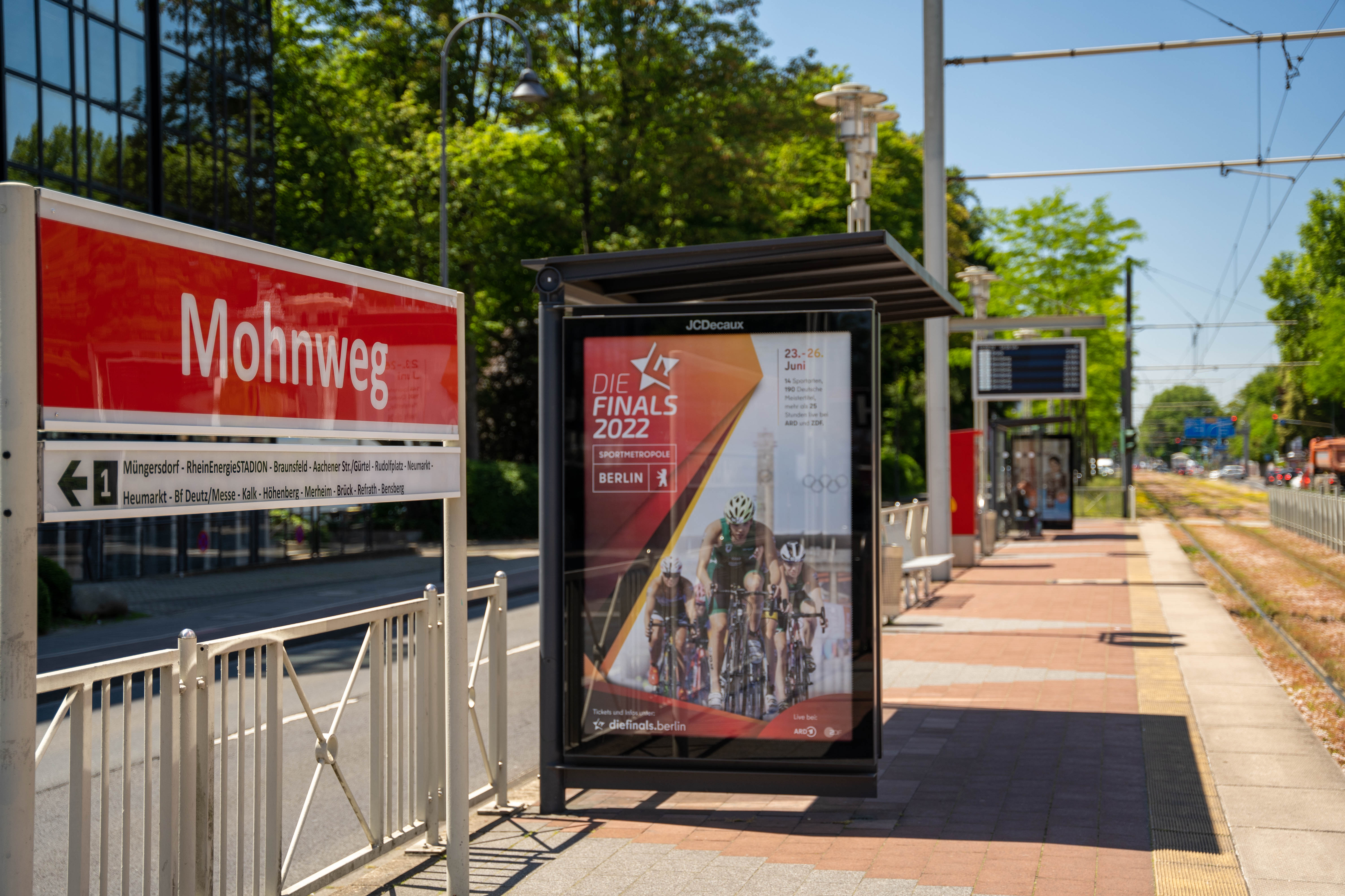 Seitlicher Blick vom Bahnsteig auf das Haltestellenschild Mohnweg Richtung Müngersdorf