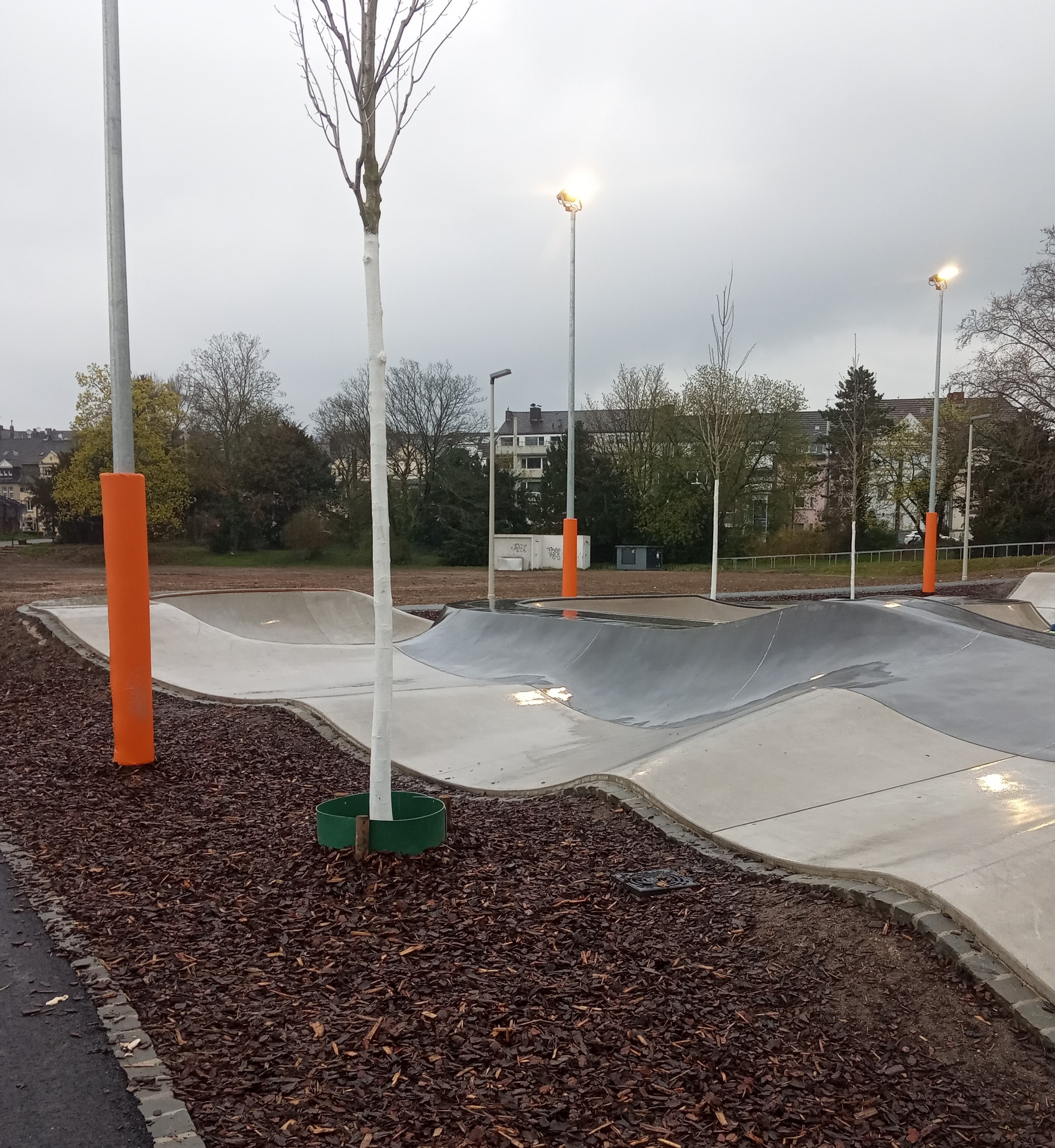 Auf dem Bild ist ein Pumptrack zu sehen, welcher sich auf eine Sportanlage befindet. Bei einem Pumptrack handelt es sich um eine speziell geschaffene Mountainbikestrecke. 