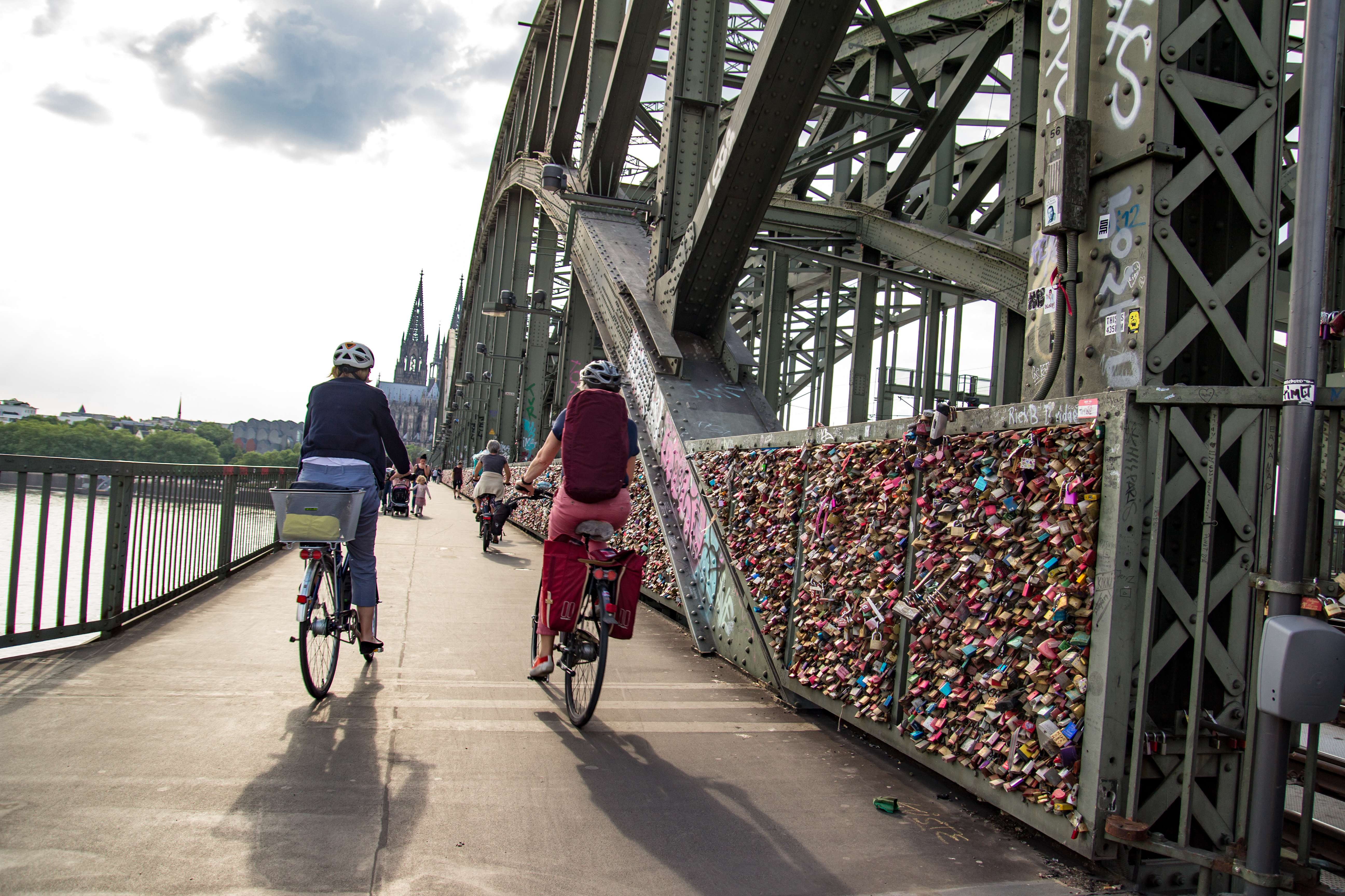 Zwei Fahrradfahrerinnen auf der Kölner Hohenzollernbrücke in Richtung Dom.