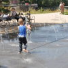 Kleines Kind läuft durch Wasserfontäne