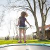 Ein Kind hüpft auf einem Trampolin in einem Garten.