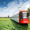 Eine rot-weiße Bahn der Kölner Verkehrsbetriebe fährt aus der Stadt Köln raus ins Grüne und die Natur. Im Hintergrund ist die Skyline von Köln mit dem Kölner Dom. Um die Bahn und die Schienen herum ist eine grüne Wiese mit kleinen, gelben Blumen und einem großen Baum.